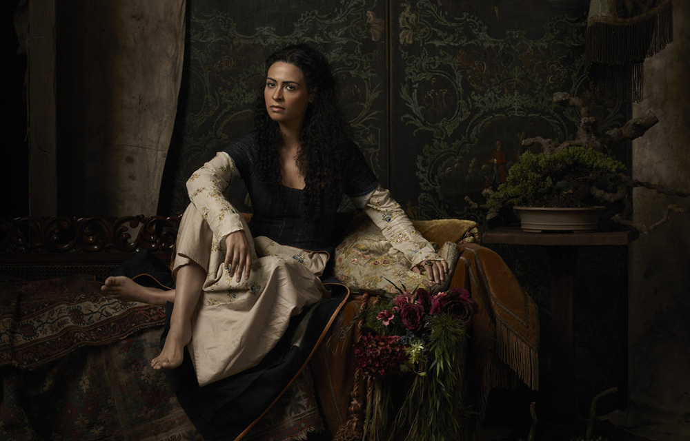 Yasmine Al Massri in Crossbones Woman sitting on richly woven rugs